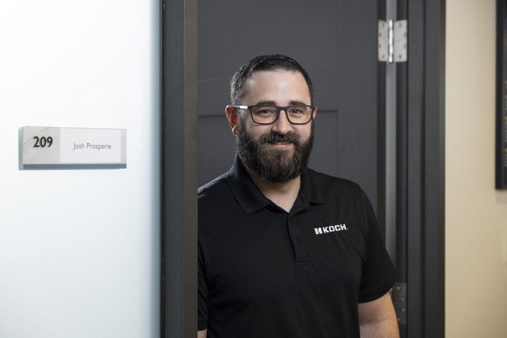 Man smiling in doorway facing the camera.