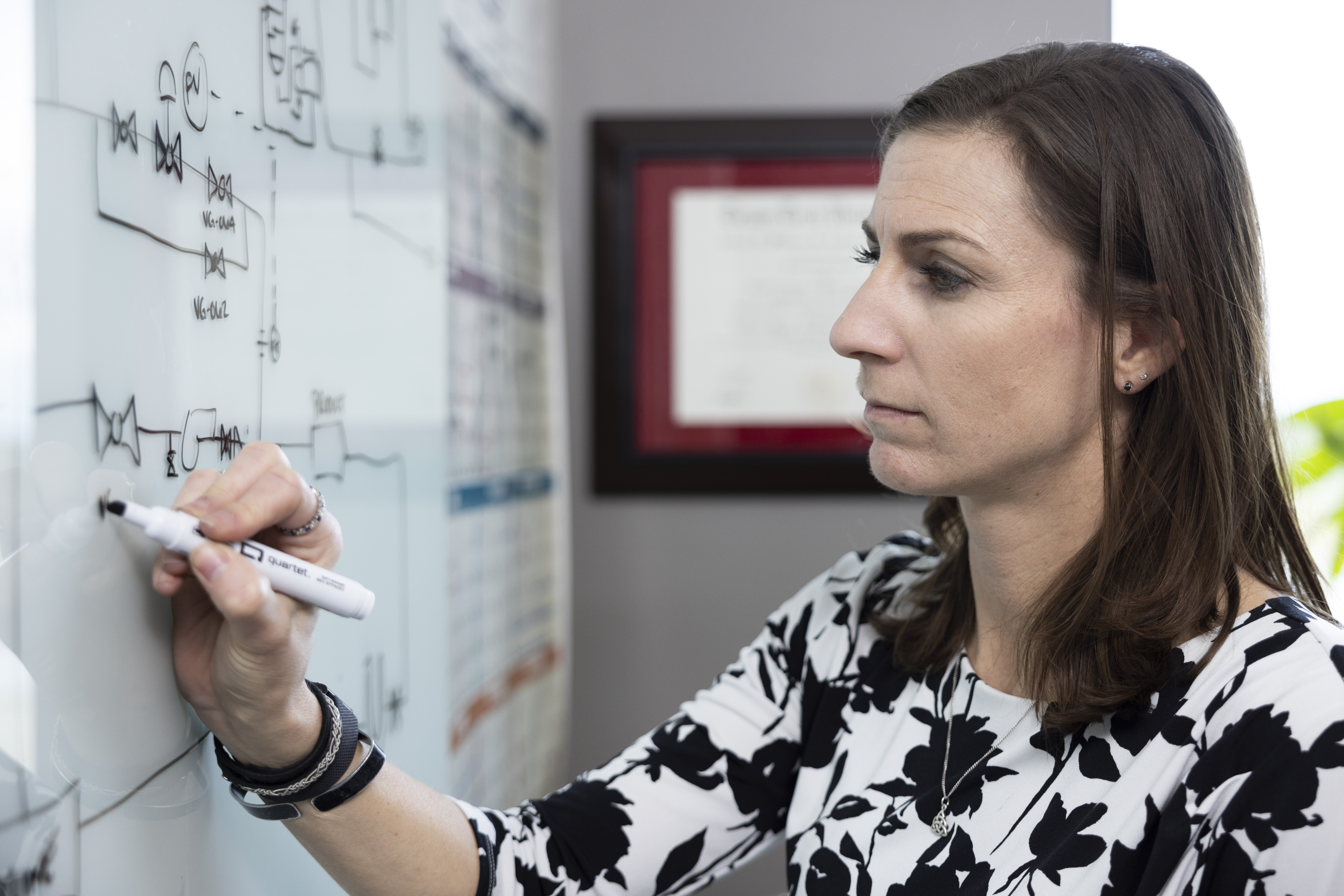 Woman engineer writing on whiteboard.